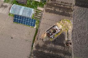 A Local Resident Plants Plants Next To A Destroyed Russian Tank, The Remains Of Which Lie In His Garden