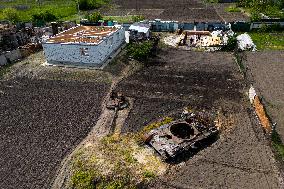A Local Resident Plants Plants Next To A Destroyed Russian Tank, The Remains Of Which Lie In His Garden