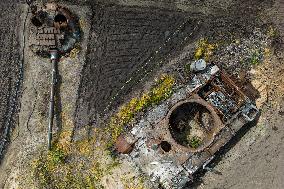A Local Resident Plants Plants Next To A Destroyed Russian Tank, The Remains Of Which Lie In His Garden