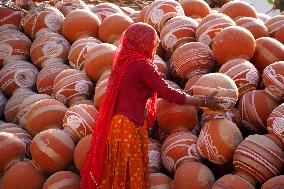 An Indian woman Arranging Pot - India