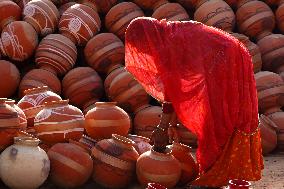 An Indian woman Arranging Pot - India