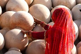 An Indian woman Arranging Pot - India