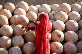 An Indian woman Arranging Pot - India