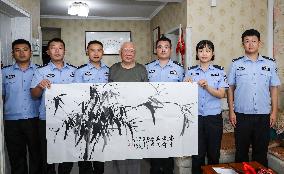 93-year-old veteran Ren Zegan presents a painting and calligraphy work to the border police in Huai 'an city, Jiangsu province,