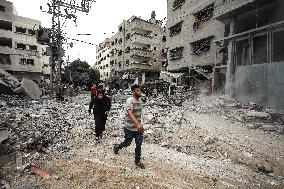 Palestinians walks infront of the rubble of destroyed buildings after an Israeli air stike in Gaza City, on October 9, 2023.