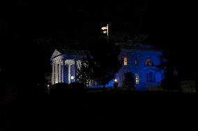 The White House in Washington, DC is illuminated in blue and white