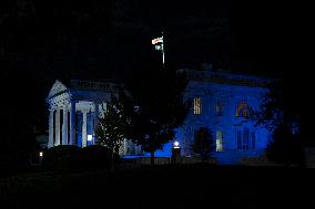 The White House in Washington, DC is illuminated in blue and white