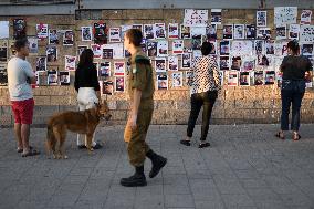 Israelis stand in front of photographs of some of those taken hostage by Hamas during their recent attacks