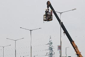 Electrician Working on an Electric Lamp Post on a Cloudy Day in West Bengal