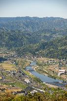 Images of farmhouses, mountain ranges, rice paddies, fields, and a river