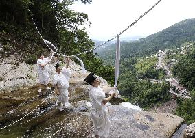 Sacred rope replace at western Japan waterfall