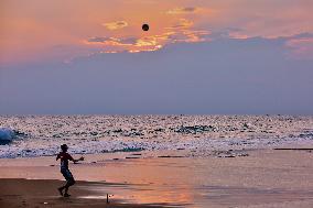 Youth Play A Game Of Football By The Ocean At Sunset In Paruthiyoor