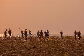 Youth Play A Game Of Football By The Ocean At Sunset In Paruthiyoor