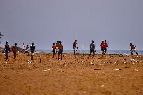 Youth Play A Game Of Football By The Ocean At Sunset In Paruthiyoor