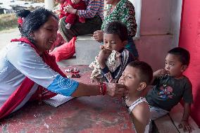 Health Worker Administers Vitamin A Capsule To Child In Nepal.