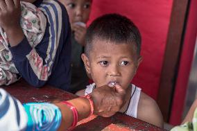 Health Worker Administers Vitamin A Capsule To Child In Nepal.