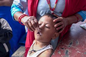 Health Worker Administers Vitamin A Capsule To Child In Nepal.