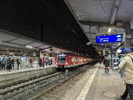 Passengers Waiting During Sleet At A Train Station On Munich