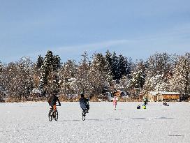 Boys Cycling On Frozen Bavarian Lake Staffelsee