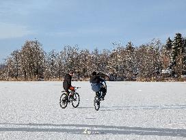 Boys Cycling On Frozen Bavarian Lake Staffelsee