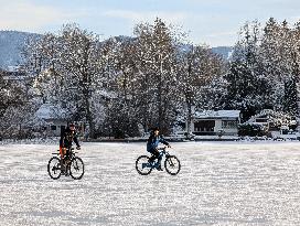 Boys Cycling On Frozen Bavarian Lake Staffelsee