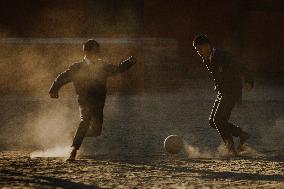 School Students Playing Football Barefoot