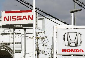Signs and logos of Honda Motor Co. and Nissan Motor Co.