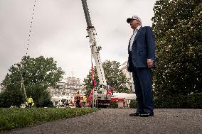 President Trump speaks to the press while workers instals a new flag pole on South Lawn