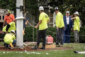 President Trump speaks to the press while workers install a new flag pole on South Lawn