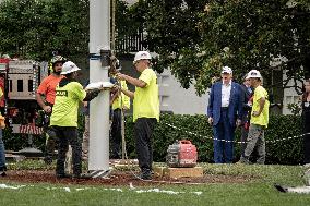 President Trump speaks to the press while workers install a new flag pole on South Lawn