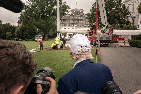 President Trump speaks to the press while workers installs a new flag pole on South Lawn