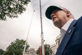 President Trump speaks to the press while workers installs a new flag pole on South Lawn