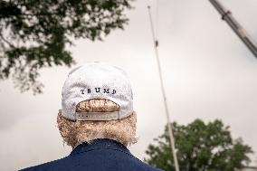 President Trump speaks to the press while workers installs a new flag pole on South Lawn