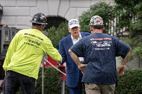 President Trump speaks to the press while workers install a new flag pole on South Lawn