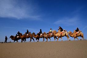 Tourists On Camels At Mingsha Mountain and Crescent Spring Scenic Area - China