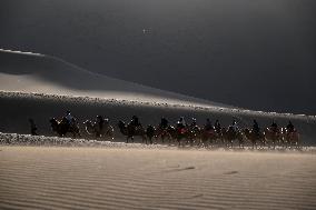 Tourists On Camels At Mingsha Mountain and Crescent Spring Scenic Area - China