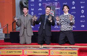Jonas Brothers Hand And Footprint In Cement Ceremony - LA