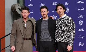 Jonas Brothers Hand And Footprint In Cement Ceremony - LA