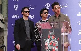 Jonas Brothers Hand And Footprint In Cement Ceremony - LA