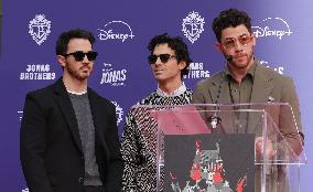 Jonas Brothers Hand And Footprint In Cement Ceremony - LA