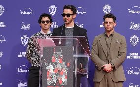 Jonas Brothers Hand And Footprint In Cement Ceremony - LA
