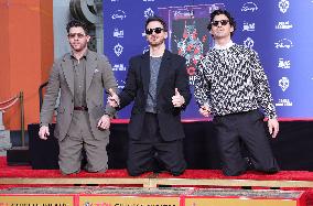 Jonas Brothers Hand And Footprint In Cement Ceremony - LA